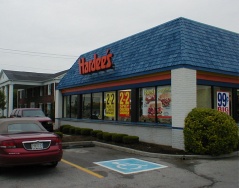 This building has undergone the architectural changes that were typical when Hardees converted a store: the pitched roof is covered with shingles to form a larger, smooth-sloped roofline, and the walls are moved outward to form a larger, cleaner look. The original corner walls can be seen behind the “99c Big...” sign. 