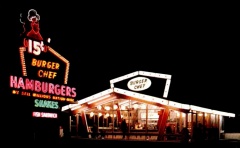 A postcard showing a nightime picture of the first store design. Notice the hamburgers were 15 cents each. [Click for larger picture]