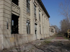 The South side of the building with the doorway and walk that leads to the south-side tracks. The express freight building is visible in the distance, as well as the remains of the red brick road.